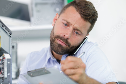 man on the phone writing on clipboard