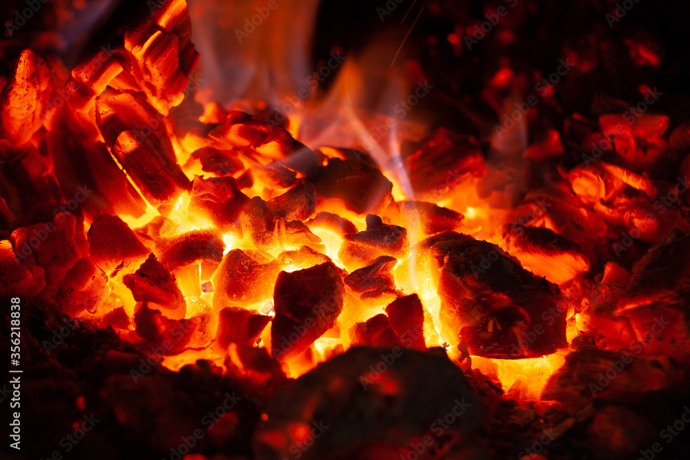 Glowing embers in hot red color, abstract background. The hot embers of burning wood log fire. Firewood burning on grill. Texture of fire fuel briquettes Glowing embers in hot red color, abstract background. The hot embers of burning wood log fire. Firewood burning on grill. Texture of fire fuel briquettes