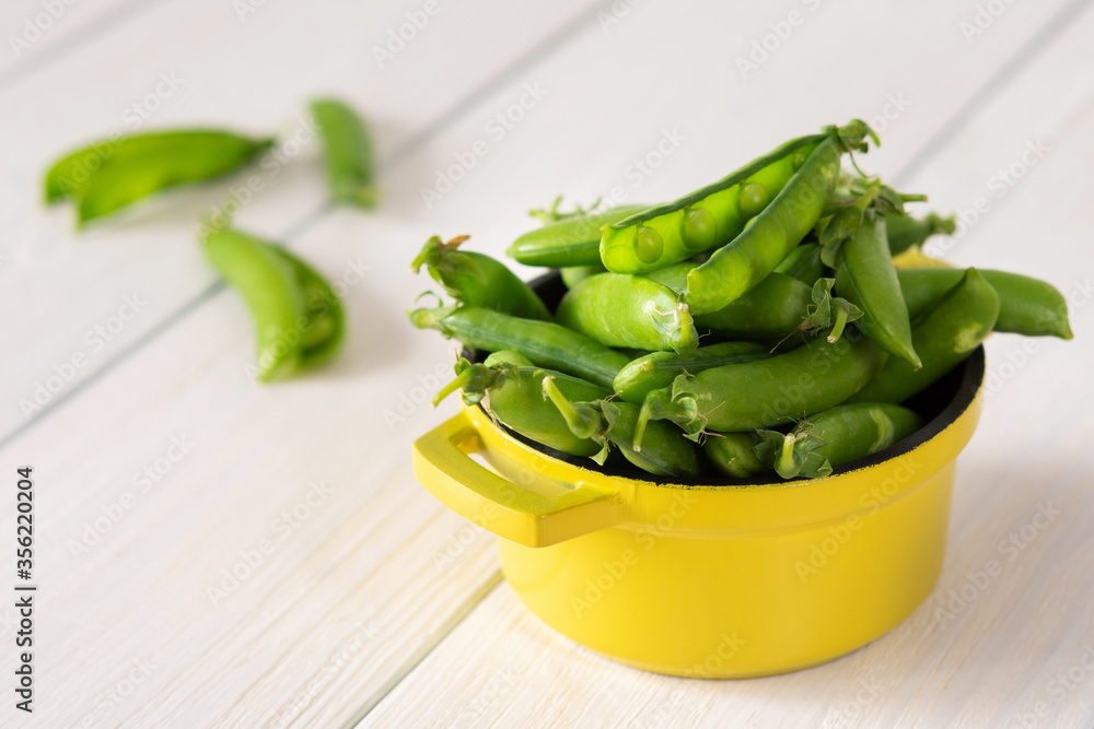 Fresh young green peas in pods in a yellow iron bowl, ripe organic vegetables Fresh young green peas in pods in a yellow iron bowl, ripe organic vegetables