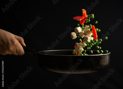 Fotografia Green peas & cottage cheese being tossed in a stir fry pan.