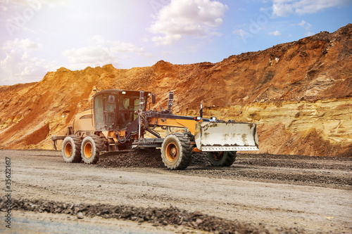 motor grader levels the ground on background of sandy quarry on the road construction  photo