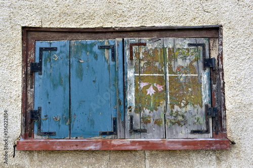 Verwitterter Fensterladen in einer alten Hausfassade photo