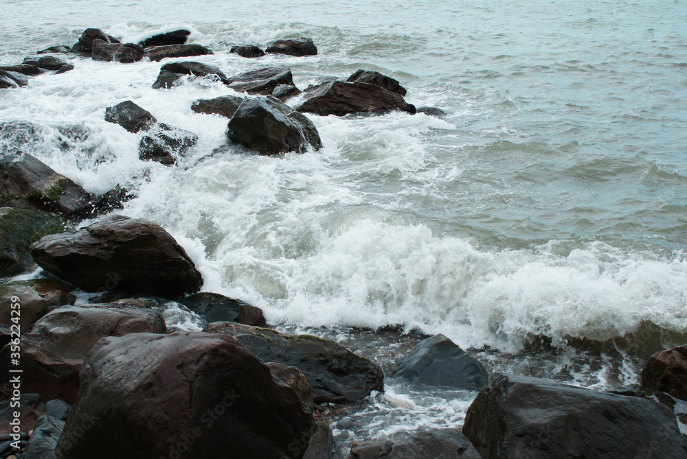 Sea, waves are breaking on stones, seashore