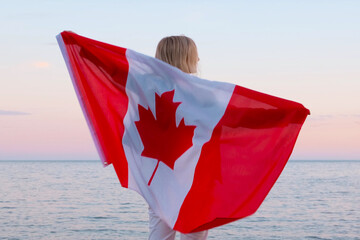 Papier peint photo Canada Back view woman waving national canada flag outdoors ocean sea sunset at summer - Canada day, country, patriotism, independence day 1th july  © FOTO_STOCKER