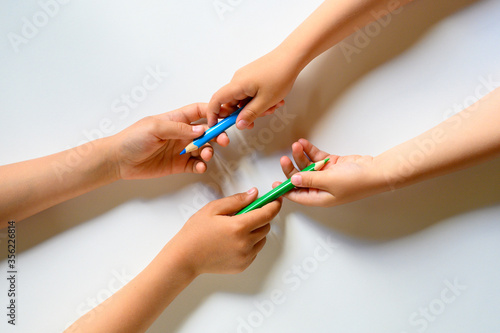 kid s hands share each other colored pencils on a white background