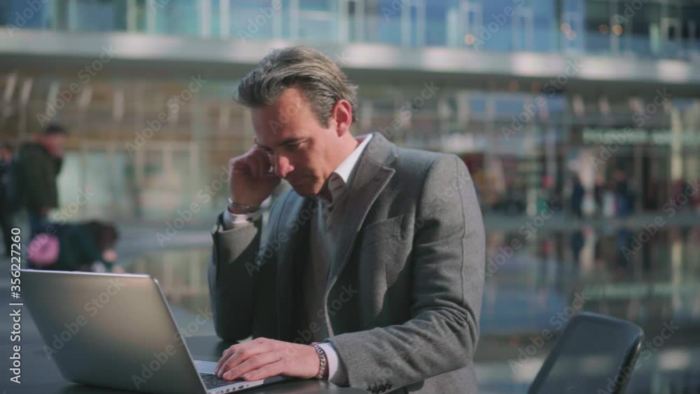 MS Businessman using laptop in sidewalk cafe in business district / Milan, Italy MS Businessman using laptop in sidewalk cafe in business district / Milan, Italy