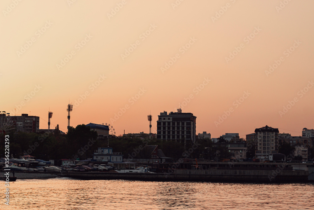 Summer sunset on the sea cost. City skyline in golden hour.
