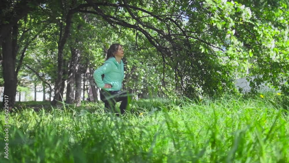 Young woman training. Woman make exercise in the spring park near blooming tree Young woman training. Woman make exercise in the spring park near blooming tree
