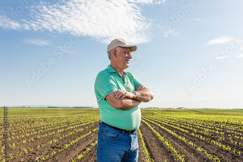Portrait of smiling senior farmer standing in corn field.