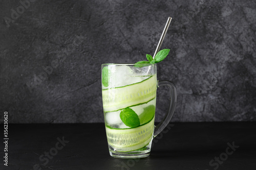 Detox cold water with sliced cucumber and mint leaves in glasses. Cucumber cocktail on dark background. Copy space