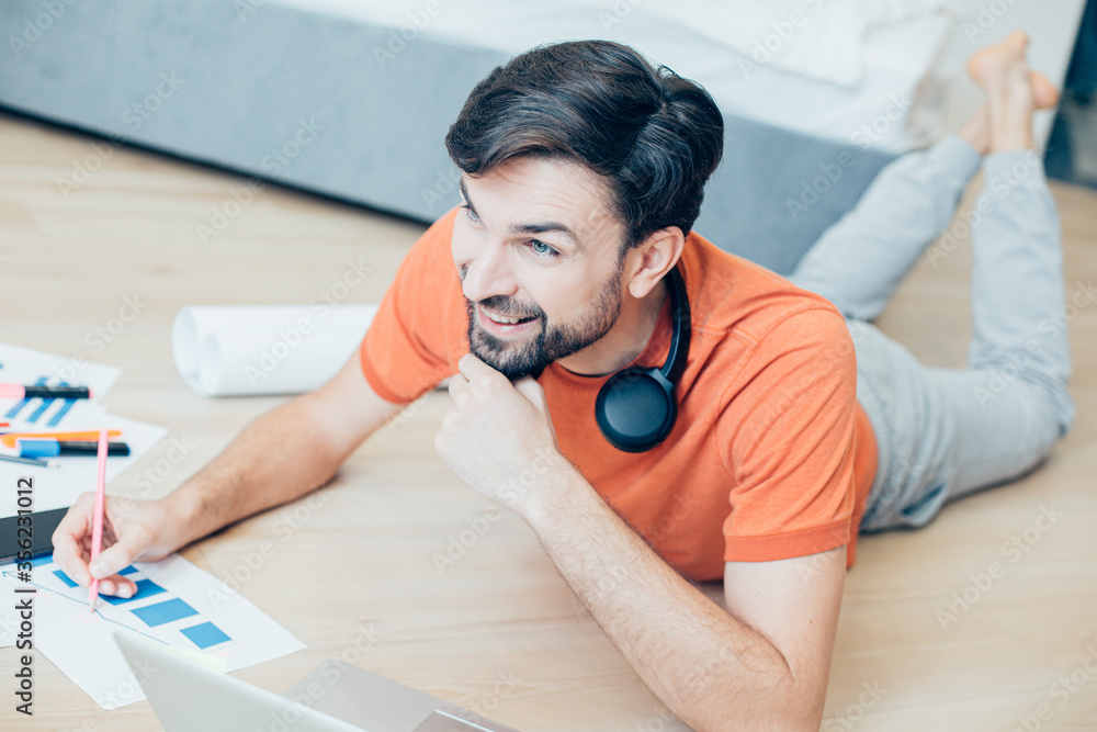 Contented man smiling while working with graphics at home Contented man smiling while working with graphics at home