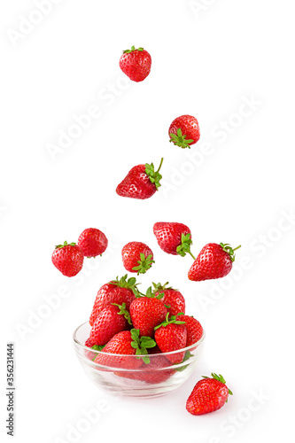 Flying fresh strowberries in transparent glass bowl isolated on white. Healthy food on white background. Delicious, sweet and ripe berry backgroung