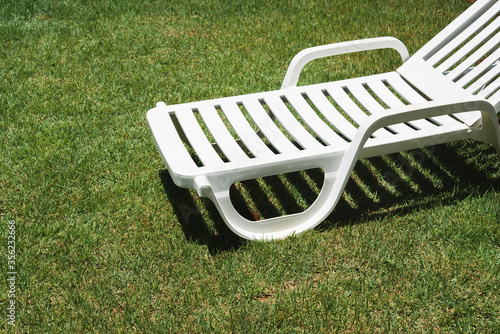 Plastic white sun chair on green natural grass on a sunny day