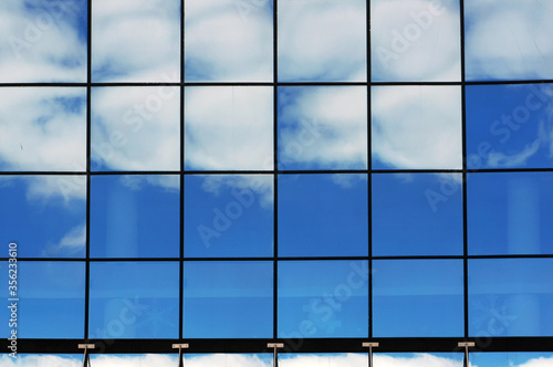 Reflections of blue sky and white clouds in windows.