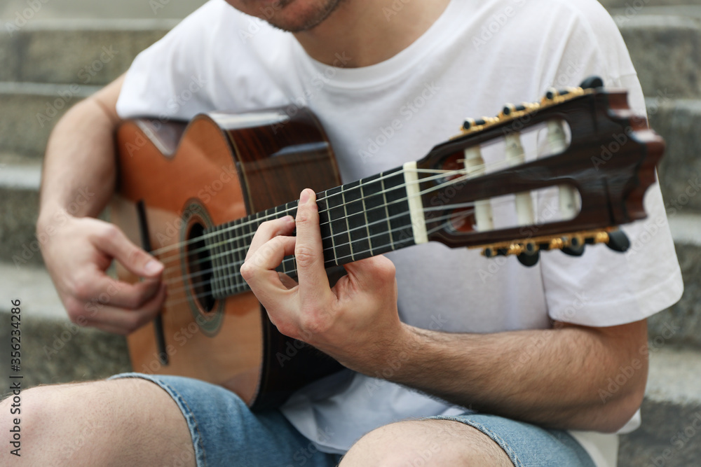 Obraz premium Young man sits on the steps and play on guitar