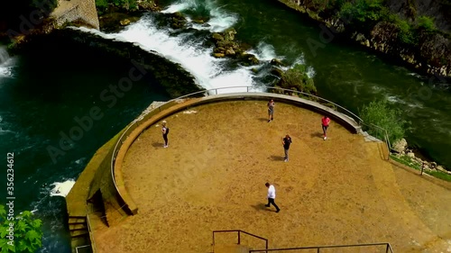 Aerial view over tourists during their visit to big waterfall of river Pliva in city of Jajce, Bosnia and Herzegovina.