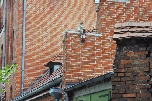 Small sculpture of an old man holding a fish sitting at brick wall of house in Torun, Poland photo