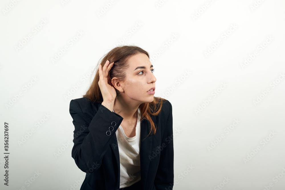 Eavesdropping, espionage, gossip, holding hand near head and looking away, what, relying on hand-ear listening the good news, trying to listen, cupping her ear. young attractive woman with brown hair Eavesdropping, espionage, gossip, holding hand near head and looking away, what, relying on hand-ear listening the good news, trying to listen, cupping her ear. young attractive woman with brown hair