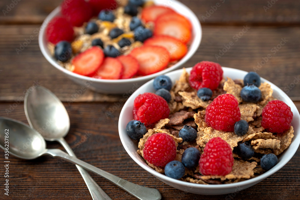 Granola with blueberries and raspberries in white bowl in dark wooden desk. Granola with blueberries and raspberries in white bowl in dark wooden desk.