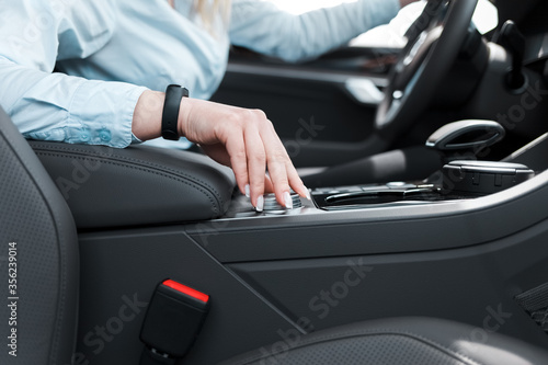 Woman holds her hand on the wheel of the car settings. Ьodern car features concept
