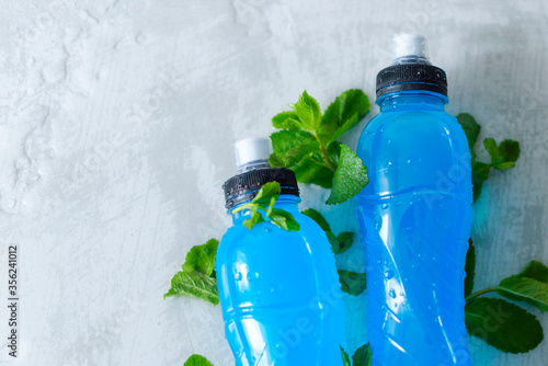 two bottles of isotonic energy drink in hand with fresh mint leaves photo