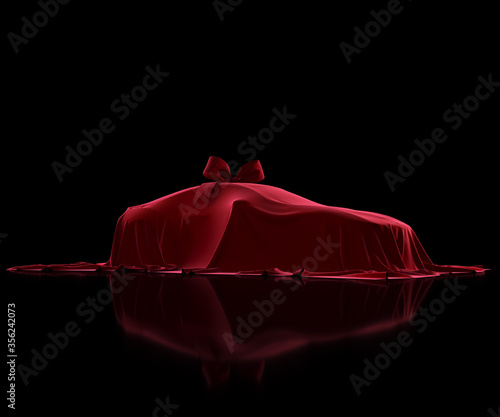 Luxury car prize covered with premium fabric on a black background. Red velvet cloth. Surprise gift with a bow-knot 