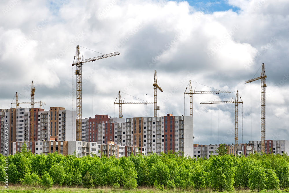 A large construction site, including several tower cranes working on the construction complex, surrounded by forest. A large construction site, including several tower cranes working on the construction complex, surrounded by forest.