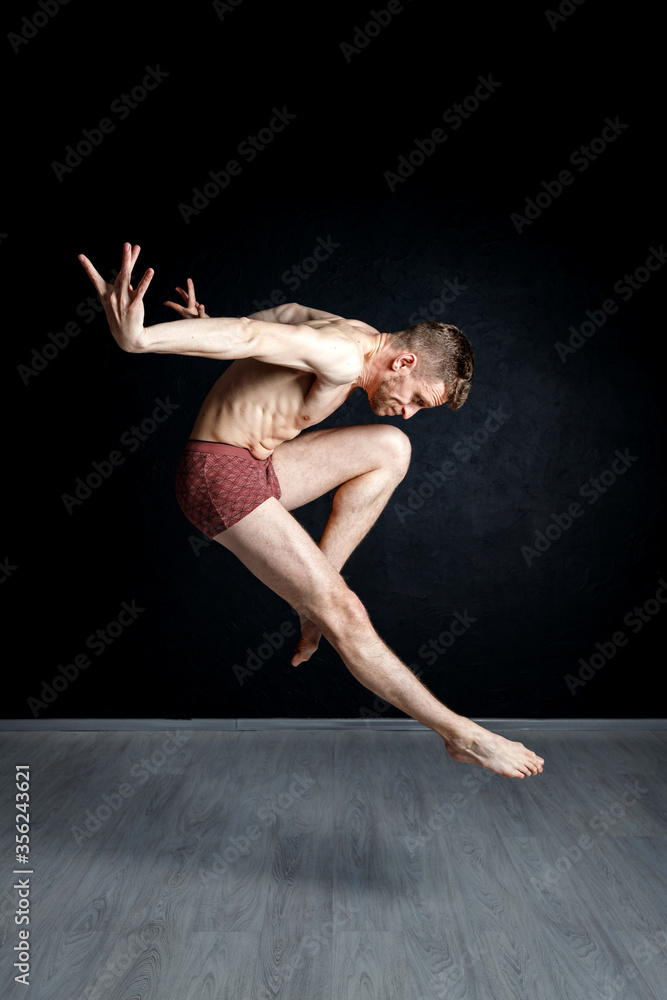 Contemporary dance positions. Young man is jumping with his hands behind  his back and leg in passe compose. Stock Photo | Adobe Stock