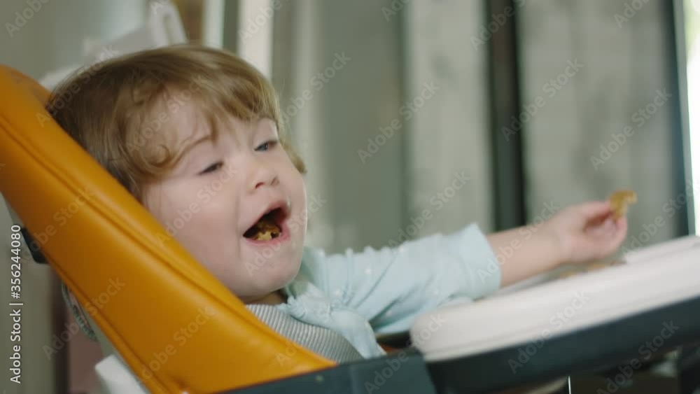 Slow motion of beautiful girl sitting on high chair and eating pancakes Slow motion of beautiful girl sitting on high chair and eating pancakes
