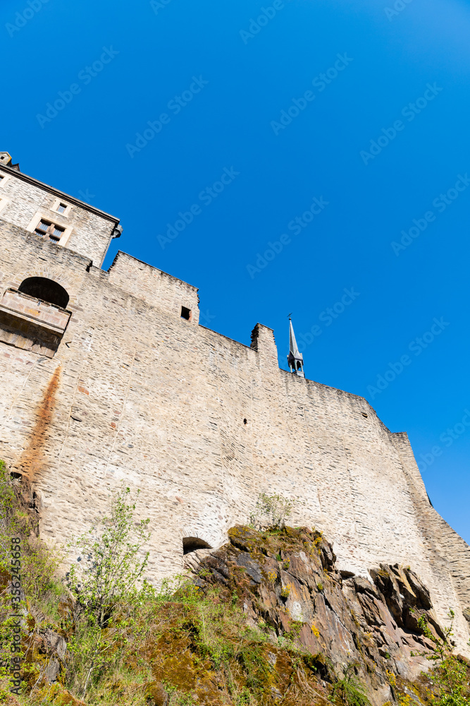 Rock covered in vegetation, brick wall, tower of Vianden castle in Luxembourg