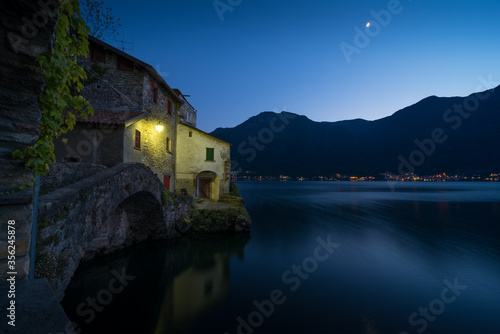 Scenic picture of Nesso on the Como lake in Italy with stone foreground at the blue hour