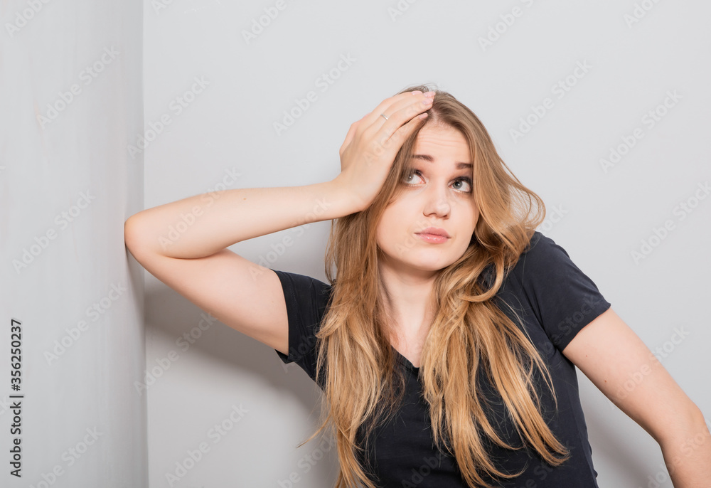 Confusion thinking with fair blond hair woman looking up with sad eyes and scratching the head. Casual neutral shirt clothing on grey studio wall for isolation portrait. Confusion thinking with fair blond hair woman looking up with sad eyes and scratching the head. Casual neutral shirt clothing on grey studio wall for isolation portrait.