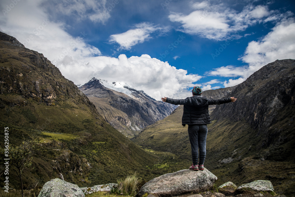 standing woman on rocks with her open arms in the middle of mountains