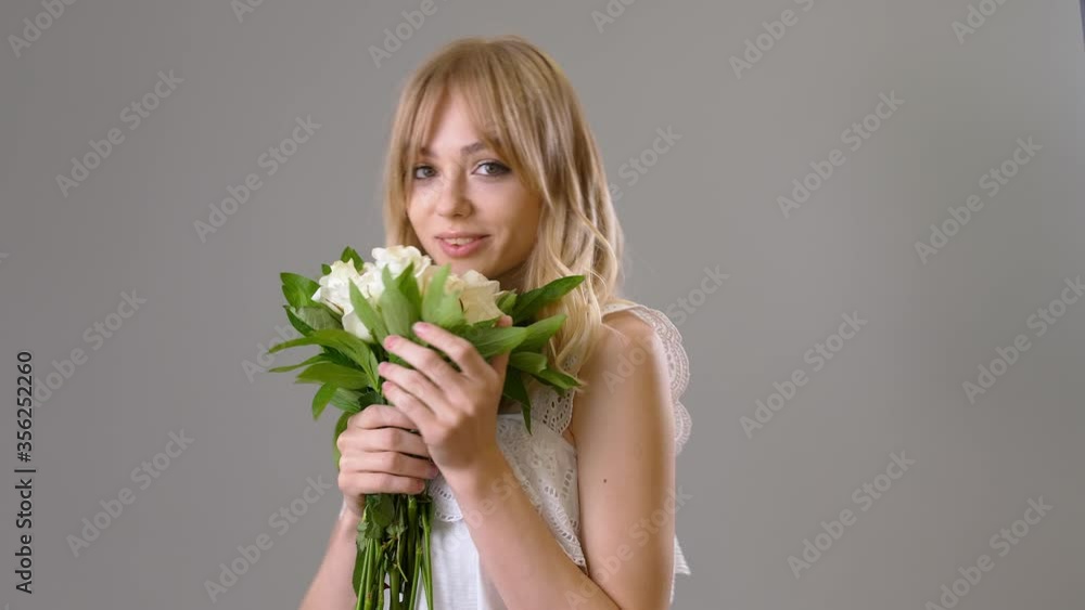 Beautiful young woman with bouquet of white roses on grey background Beautiful young woman with bouquet of white roses on grey background