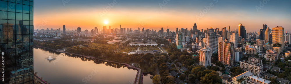 Naklejka premium Szeroki panoramiczny widok na Bangkok, Tajlandia. Pejzaż miejski z publicznym parkiem i wieżowcami o zachodzie słońca.