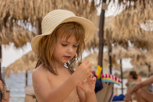 Beautiful little girl with hat on the beach.