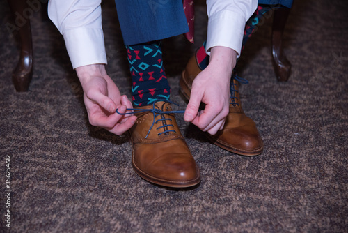 Preparing the groom puts on shoes.