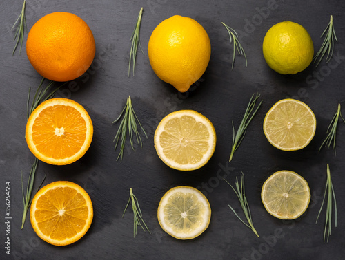 Close up of sliced citrus fruits orange, lemon and lime on dark black background.