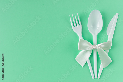 Three plastic cutlery with a bow on a green background.