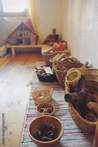 Baskets with wooden toys from Waldorf pedagogy and a wooden house. photo