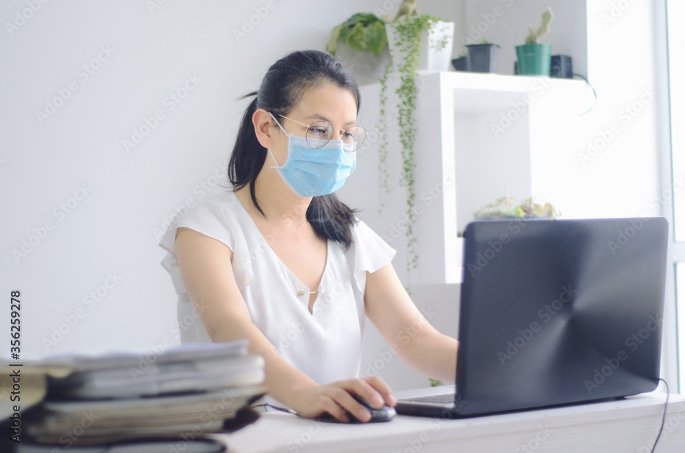 Joven mujer con máscara trabajando desde su casa en la computadora portátil durante la pandemia. Joven ejecutiva con máscara en el trabajo durante la pandemia por COVID 19. Joven mujer con máscara trabajando desde su casa en la computadora portátil durante la pandemia. Joven ejecutiva con máscara en el trabajo durante la pandemia por COVID 19.