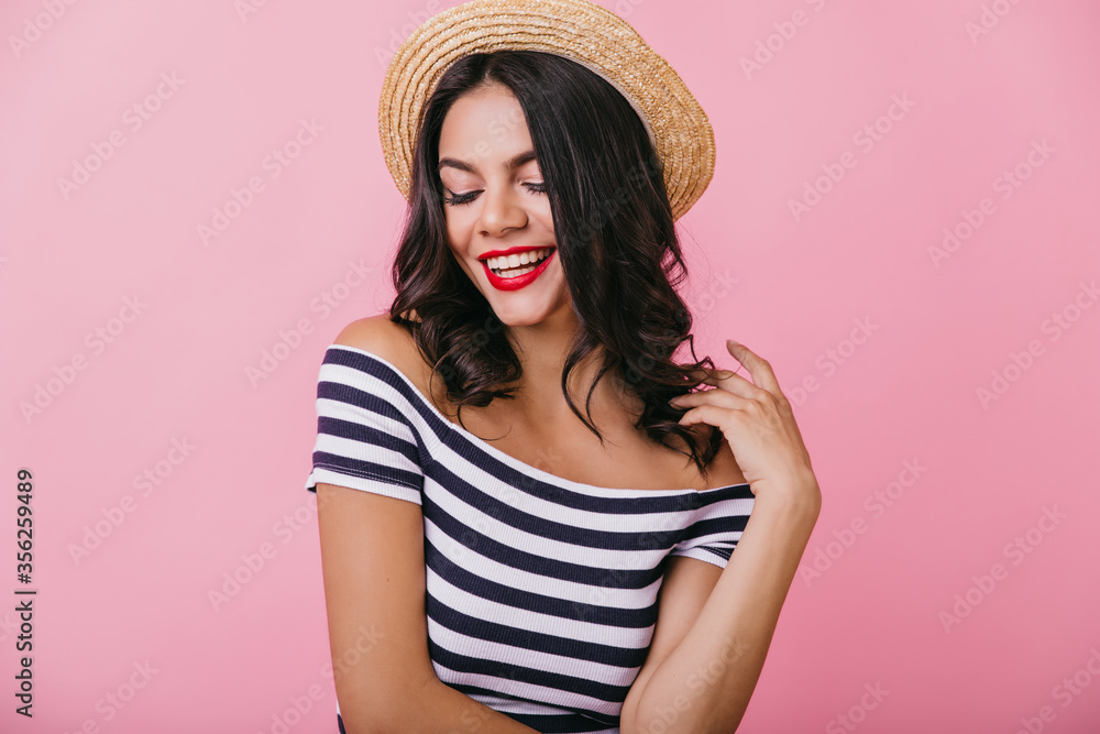Glamorous woman with cheerful smile posing with eyes closed. Indoor shot of carefree lady with trendy makeup isolated on pink background. Glamorous woman with cheerful smile posing with eyes closed. Indoor shot of carefree lady with trendy makeup isolated on pink background.