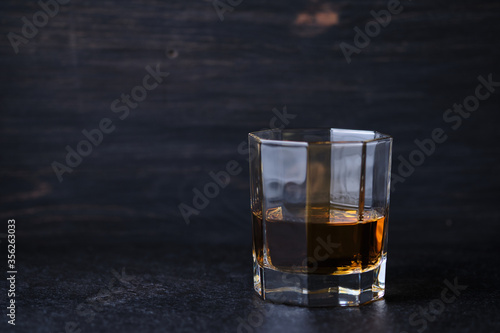 Glass of whiskey on a wooden table in a bar. Bar counter with an alcoholic drink.