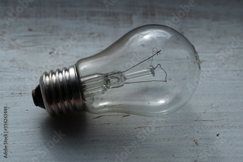 Tableau sur toile Burned out old light bulb lying on the wooden painted white surface