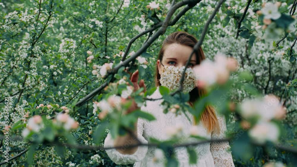 Young girl with blue eyes in the flower mask in the cherry orchard. Young girl with blue eyes in the flower mask in the cherry orchard.