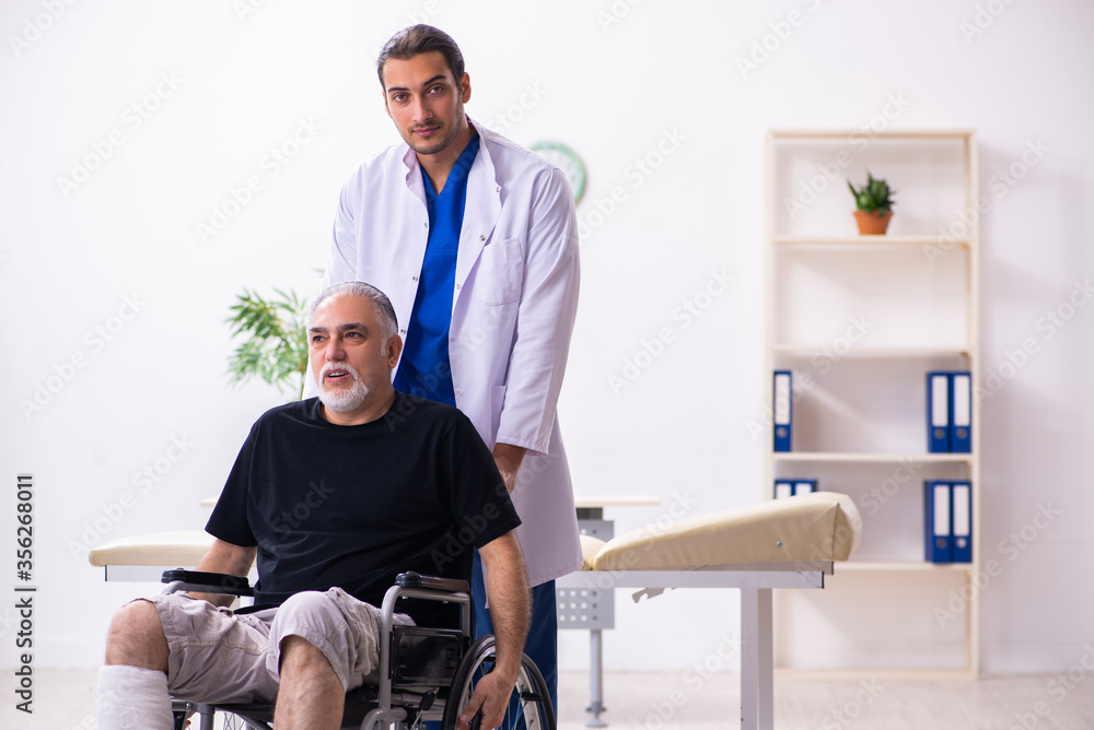 Obraz premium Old injured man visiting young male doctor traumatologist