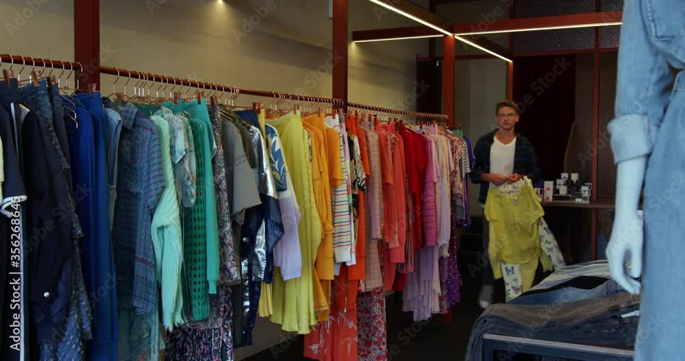 WS Man hanging clothing on clothes rack in boutique at King's Cross / London, UK WS Man hanging clothing on clothes rack in boutique at King's Cross / London, UK