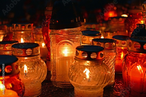 A row of blurred yellow, orange and red grave candles (lanterns) on a cemetery - a symbol of remembrance