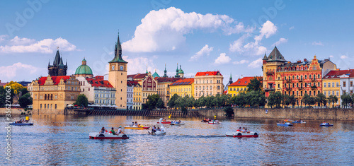Scenic embankment in Prague city with paddle boats on Vltava river and Charles bridge; Historical center of Prague, buildings and landmarks of old town, Prague, Czech Republic