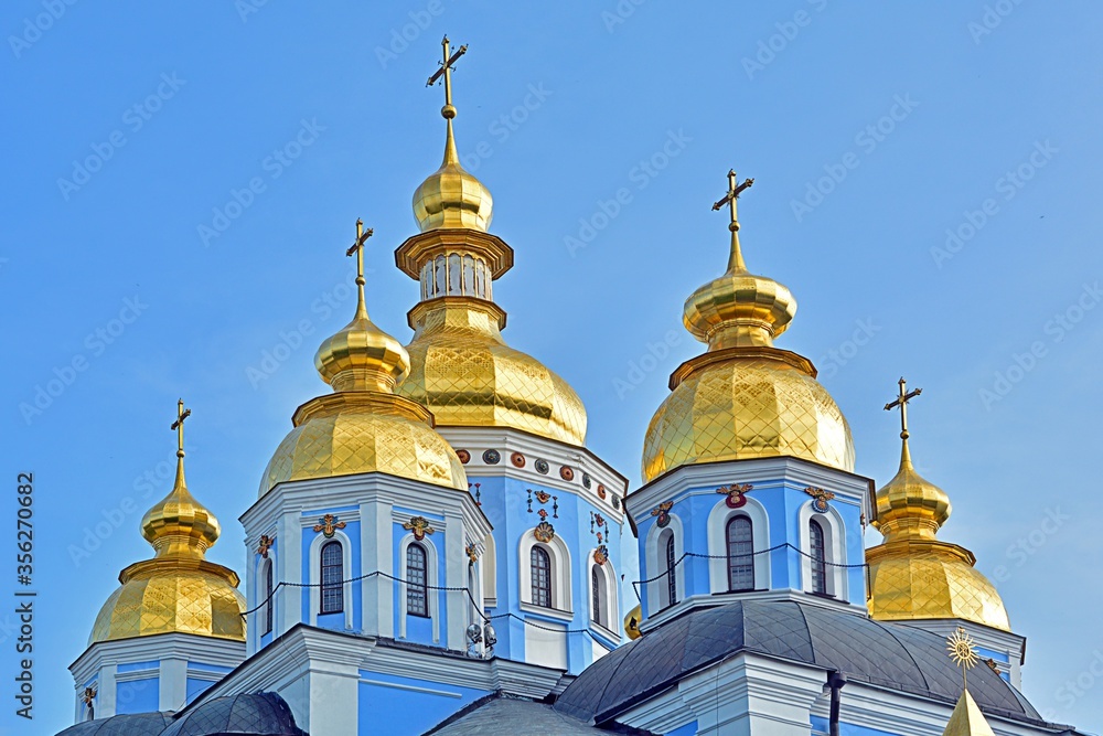 Eastern orthodox crosses on gold domes (cupolas) with a blue sky